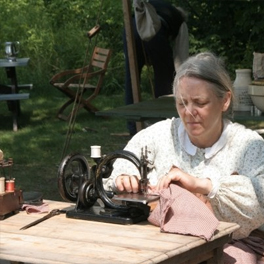 Woman sewing with a period sewing machine